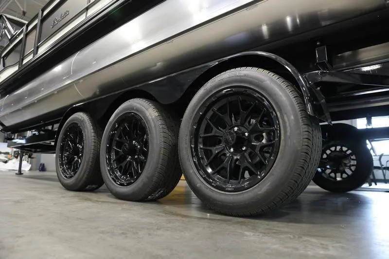 Slide: The Image of 2024 Barletta LUSSO L25M pontoon boat with black triple-axle trailer. - 5