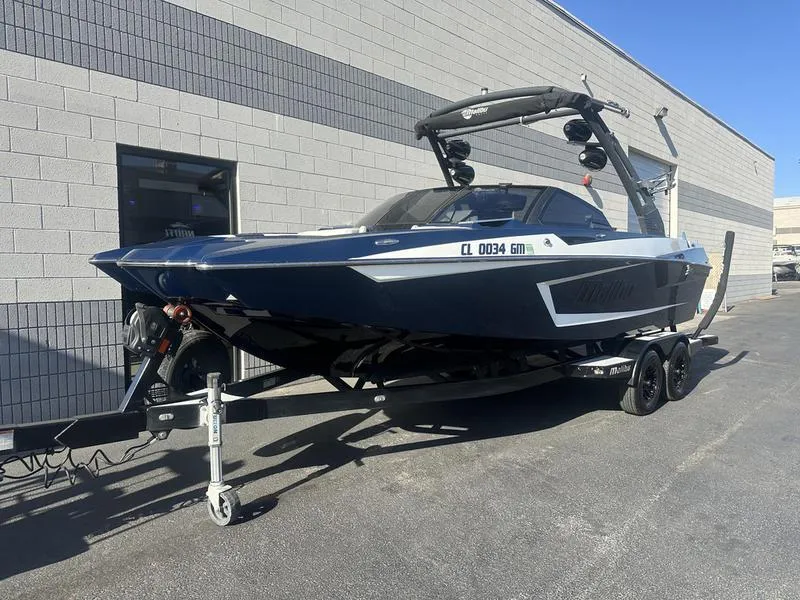 Slide: The Image of 2024 Malibu 23 MXZ boat on a trailer outside a building. - 1