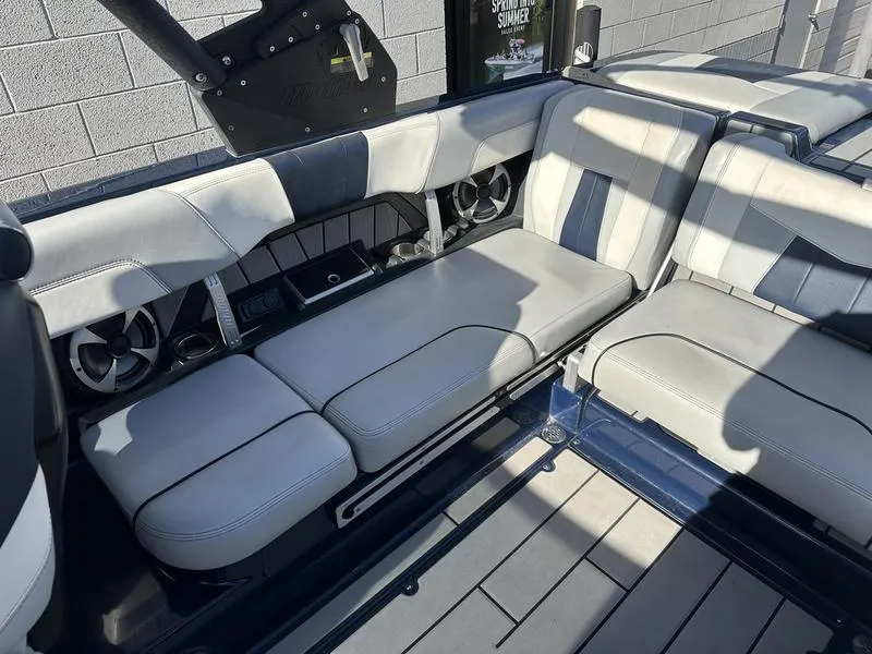 Slide: The Image of 2024 Malibu 23 MXZ boat interior with gray and white seating and built-in speakers. - 3