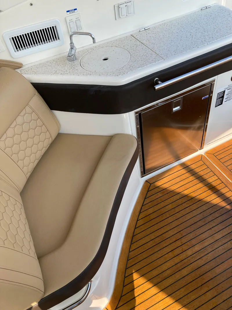 Slide: The Image of 2020 Sea Ray 320 Sundancer interior with seating, kitchenette, and wood flooring. - 14