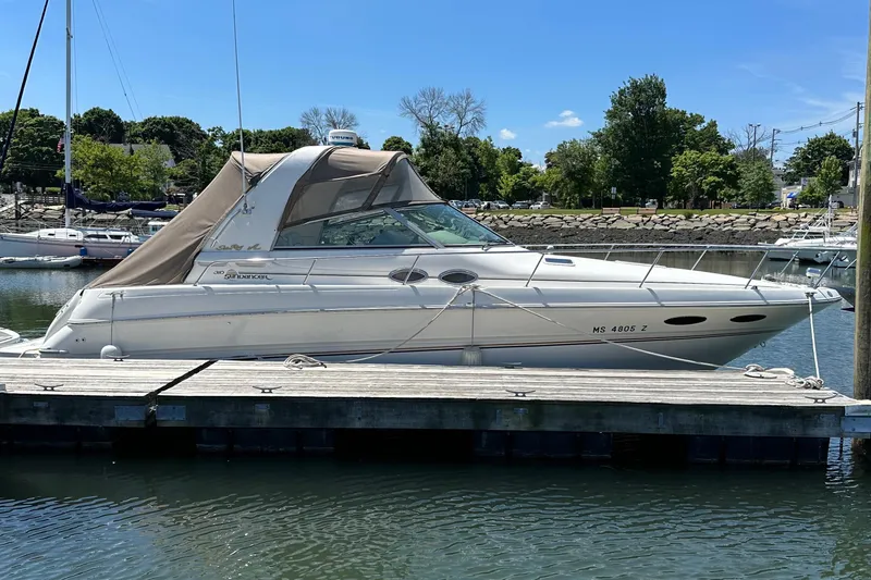 Slide: The Image of 1999 Sea Ray 310 Sundancer docked at a marina on a sunny day. - 1