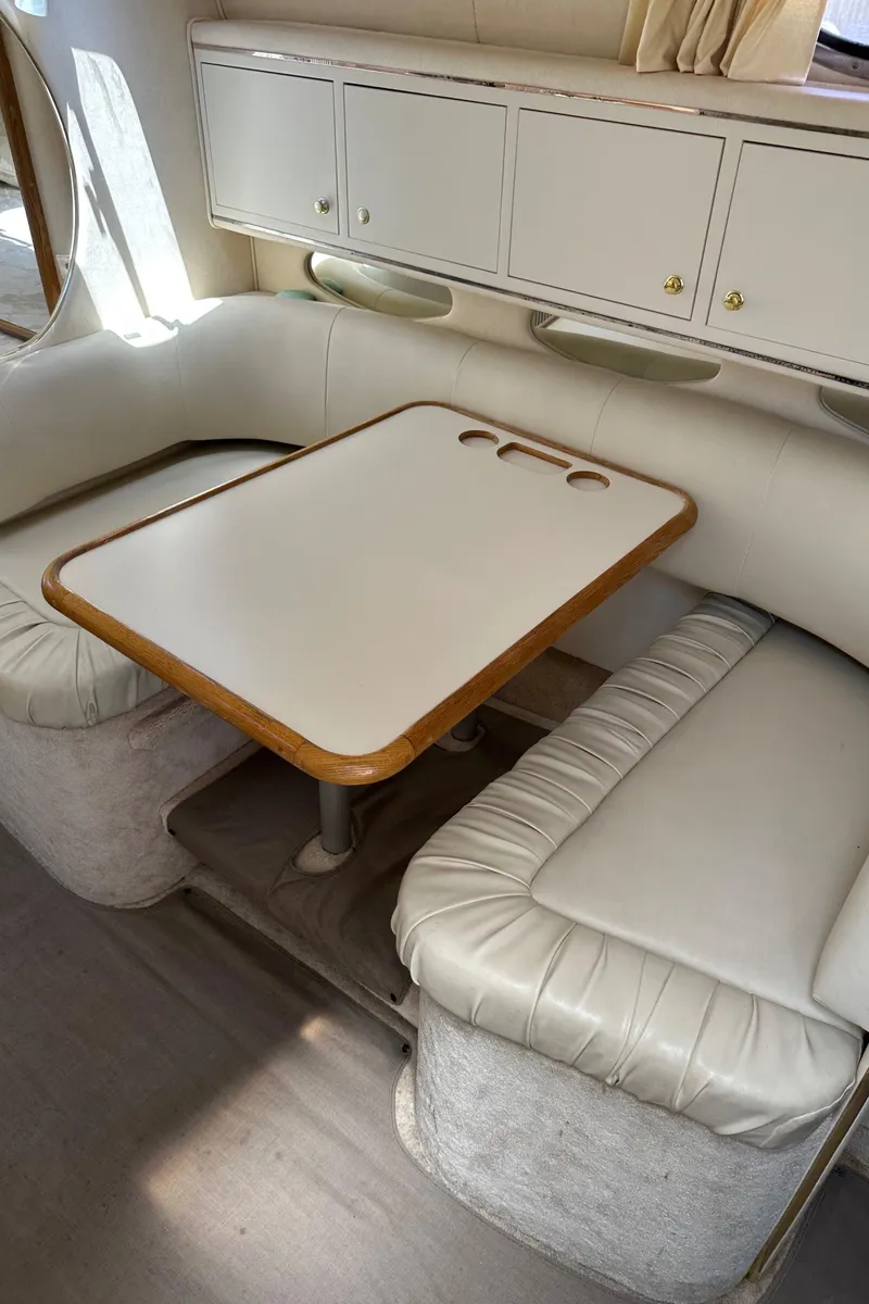 Slide: The Image of 1999 Sea Ray 310 Sundancer interior with white leather seating and dining table. - 16