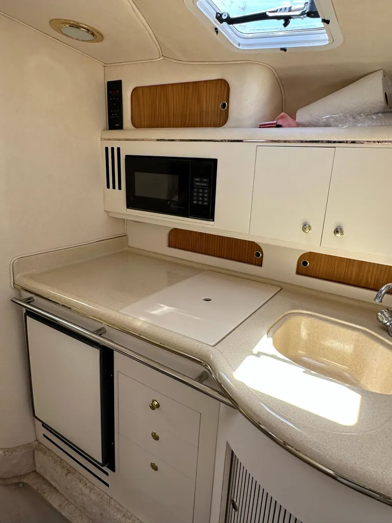 Slide: The Image of 1999 Sea Ray 310 Sundancer galley with microwave, sink, and storage cabinets. - 19