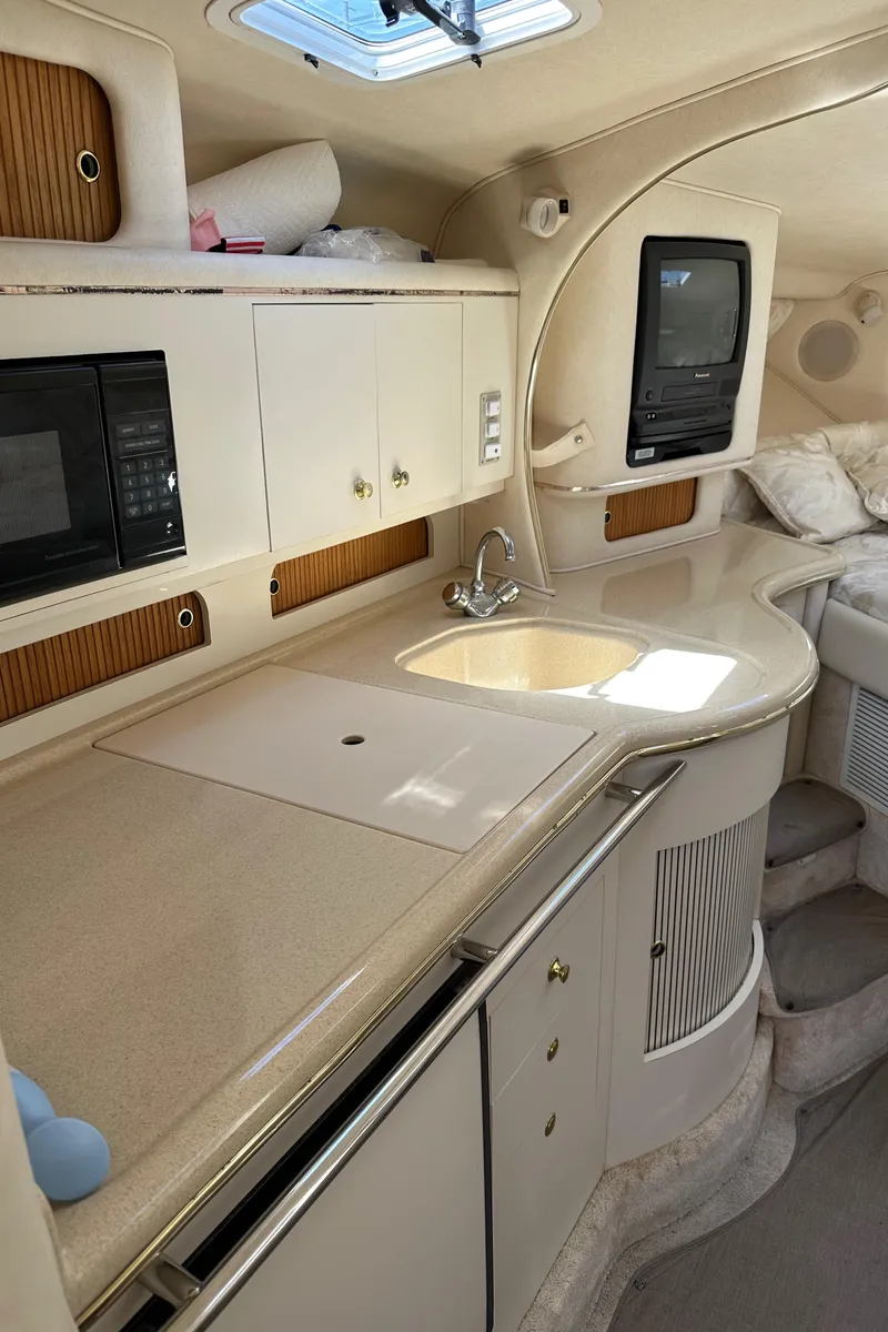 Slide: The Image of 1999 Sea Ray 310 Sundancer interior with kitchenette, sink, and built-in appliances. - 20