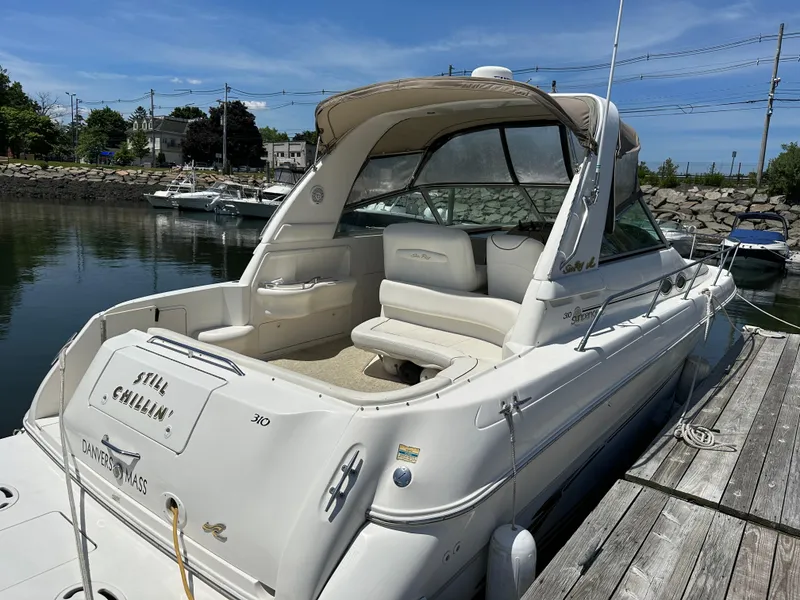 Slide: The Image of 1999 Sea Ray 310 Sundancer docked, featuring sleek design and spacious seating. - 3
