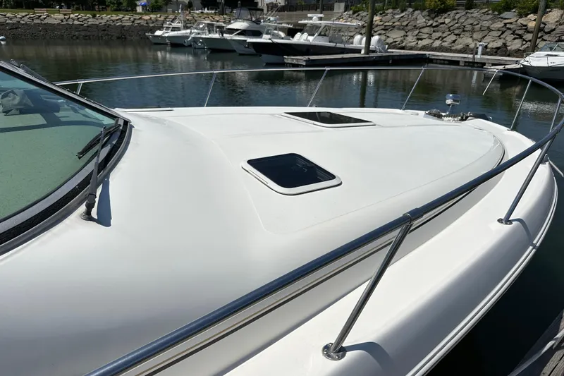 Slide: The Image of 1999 Sea Ray 310 Sundancer boat docked at marina, showing sleek deck design. - 5