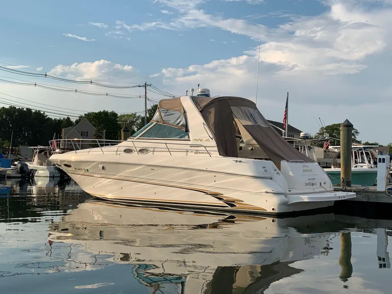 The Image of 1999 Sea Ray 310 Sundancer boat docked in a marina under a partly cloudy sky. - 0