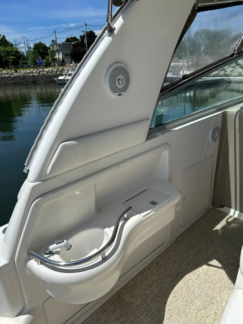 Slide: The Image of 1999 Sea Ray 310 Sundancer boat interior with sink and speaker, docked by calm water. - 10