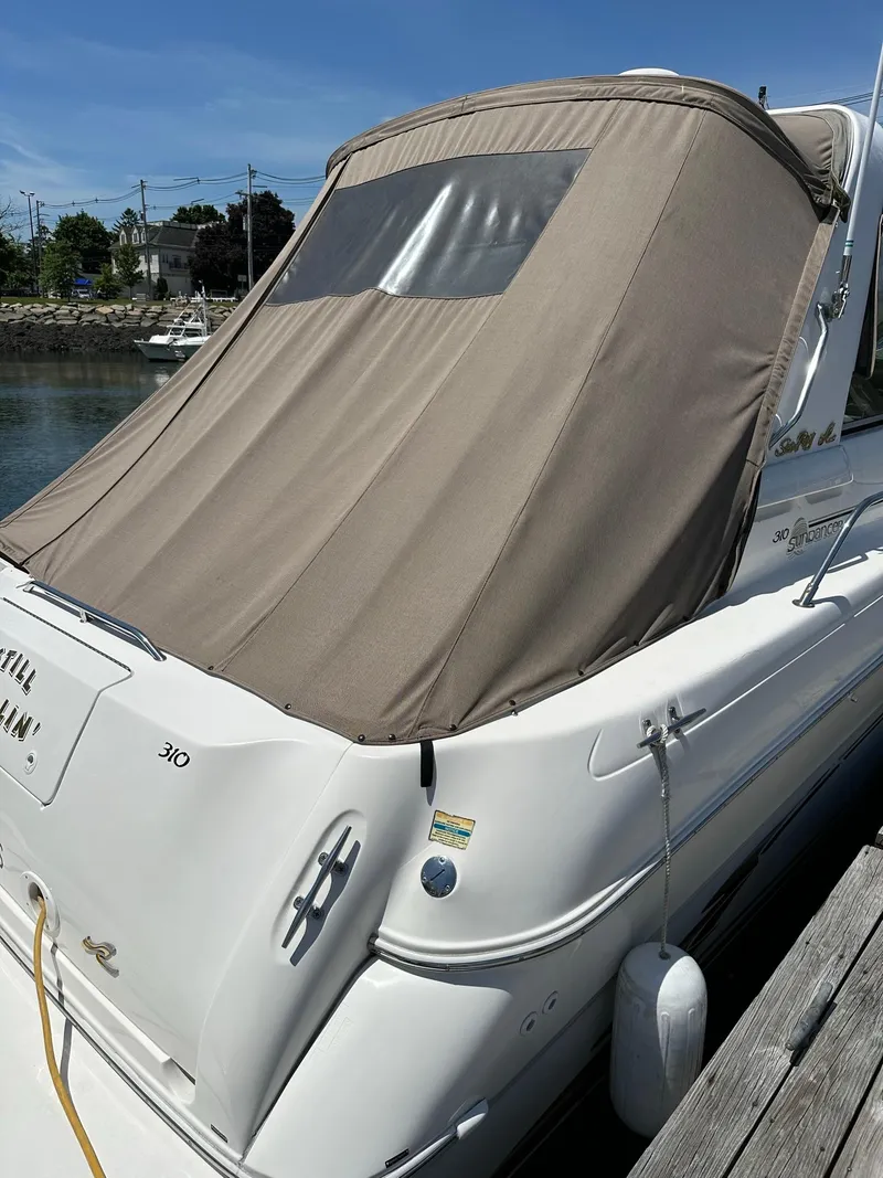 Slide: The Image of 1999 Sea Ray 310 Sundancer with beige canvas cover docked at marina. - 2
