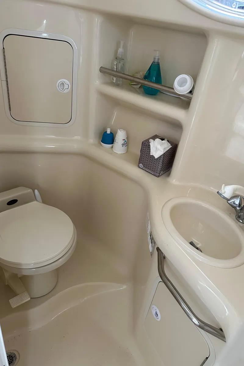 Slide: The Image of 1999 Sea Ray 310 Sundancer bathroom with toilet, sink, and storage shelves. - 23