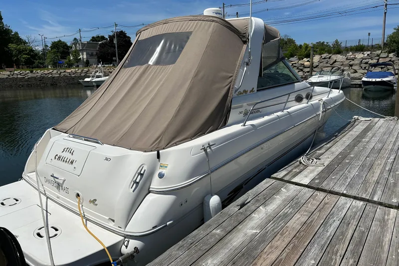 Slide: The Image of 1999 Sea Ray 310 Sundancer docked at marina, beige canopy, calm water background. - 4
