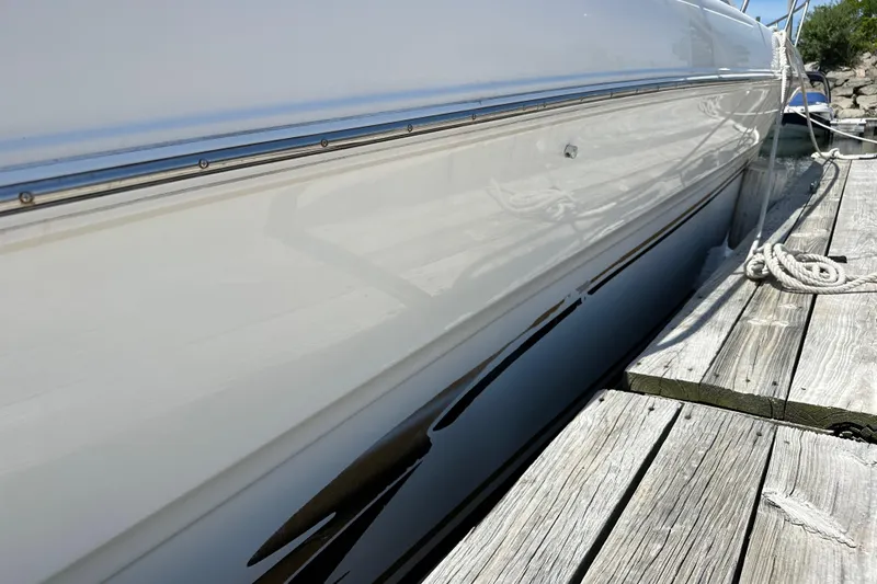 Slide: The Image of 1999 Sea Ray 310 Sundancer docked, showcasing sleek white hull and wooden pier. - 8