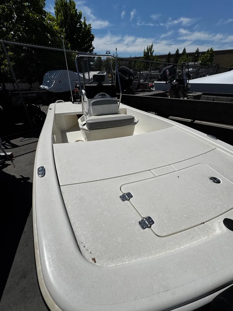 Slide: The Image of 2024 Mako Pro Skiff 17 CC boat with center console, parked outdoors. - 2