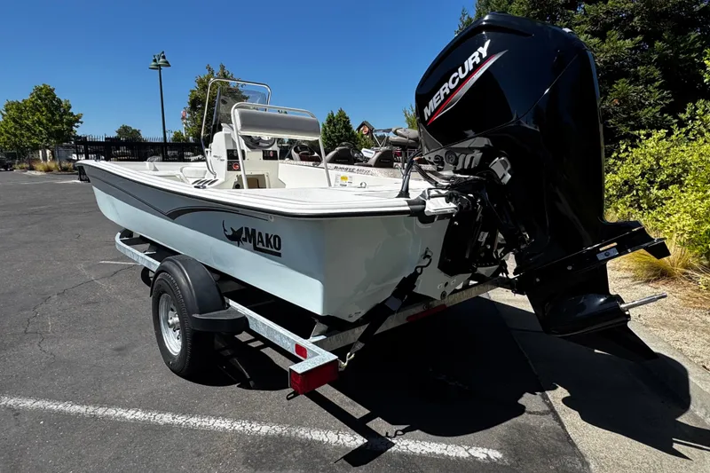 Slide: The Image of 2024 Mako Pro Skiff 17 CC boat on trailer with Mercury engine, parked outdoors. - 4