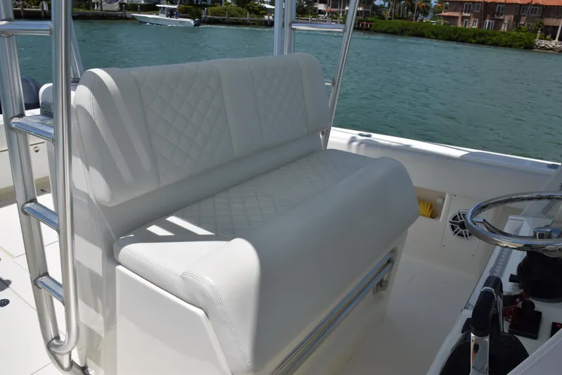 Slide: The Image of 2015 SeaVee 370z boat with white cushioned seating and steering wheel, docked near waterfront homes. - 29