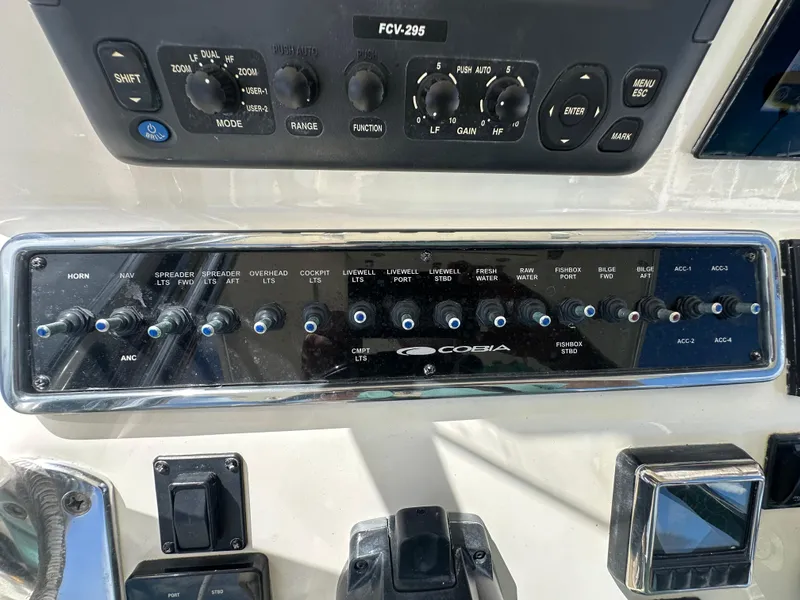 Slide: The Image of Control panel of a 2016 Cobia 296CC boat with various switches and dials. - 17