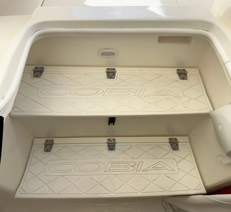 Slide: The Image of 2016 Cobia 296CC boat storage compartments with Cobia logo. - 35