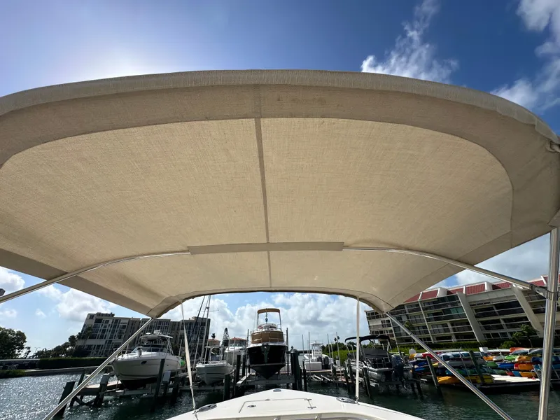 Slide: The Image of 2016 Cobia 296CC boat with canopy docked at marina on a sunny day. - 45