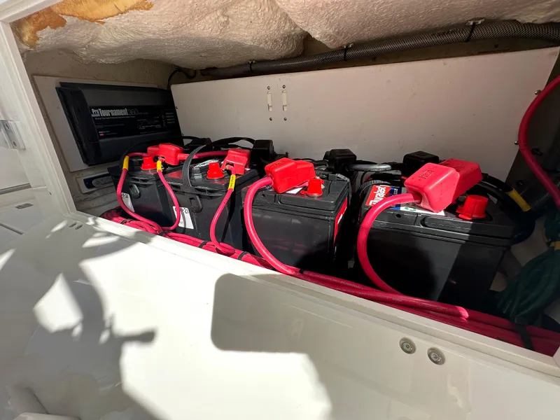 Slide: The Image of Battery compartment of a 2016 Cobia 296CC boat with multiple batteries and red cables. - 48