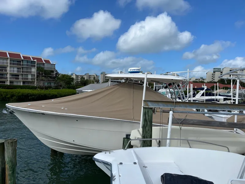 Slide: The Image of 2016 Cobia 296CC boat docked with cover, clear sky, waterfront buildings in background. - 7