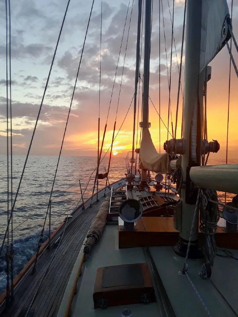 Slide: The Image of 1983 Cherubini Schooner sailing at sunset on calm ocean waters. - 15