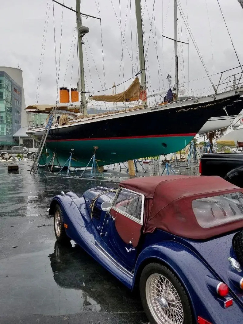 Slide: The Image of 1983 Cherubini Schooner docked near a classic blue convertible car. - 20