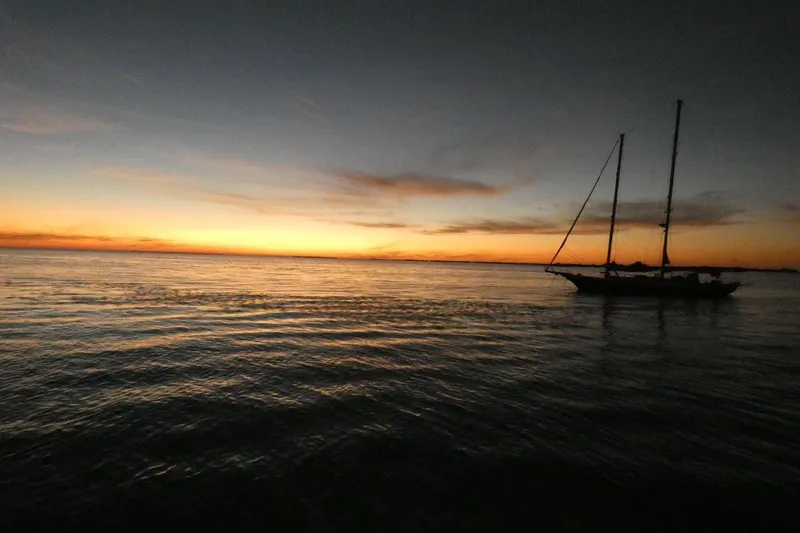 Slide: The Image of Cherubini Schooner 1983 sailing at sunset on calm waters. - 25