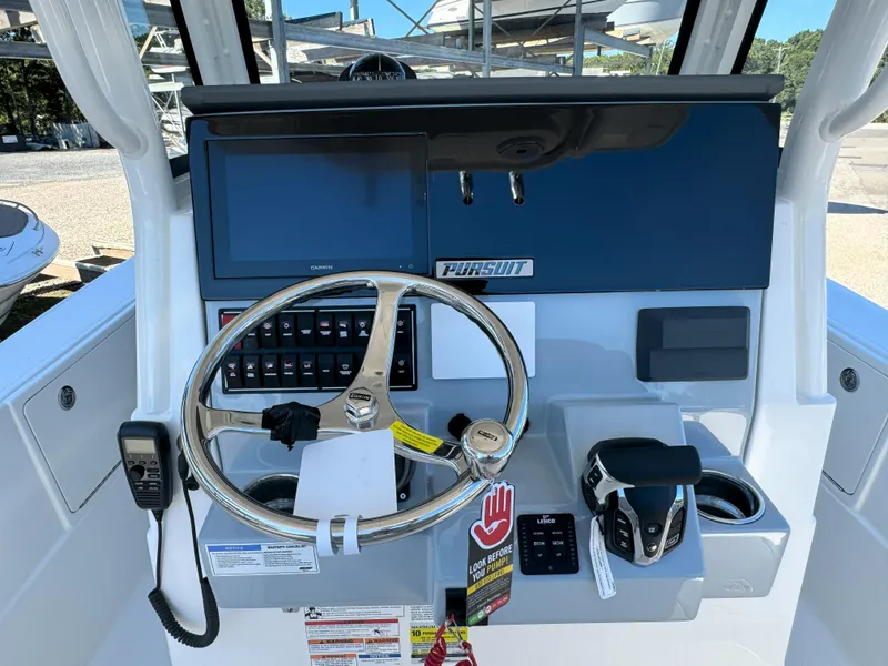 Slide: The Image of 2025 Pursuit S 248 boat dashboard with Garmin display and steering wheel. - 16