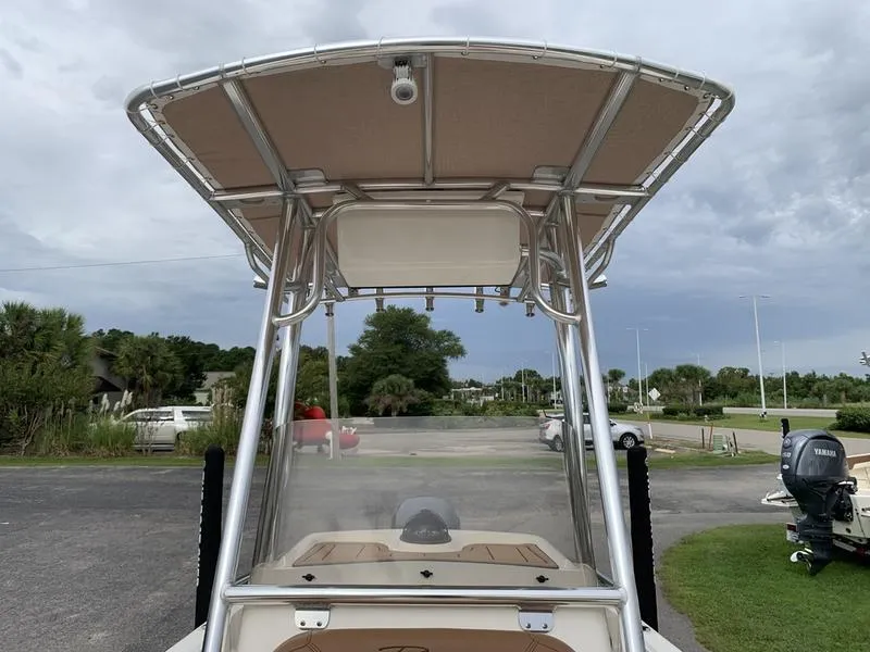 Slide: The Image of 2025 Pioneer Islander 180 boat with T-top, parked outdoors. - 25