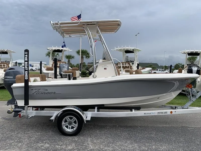 Slide: The Image of 2025 Pioneer Islander 180 boat on trailer, displayed outdoors with flags and palm trees. - 5