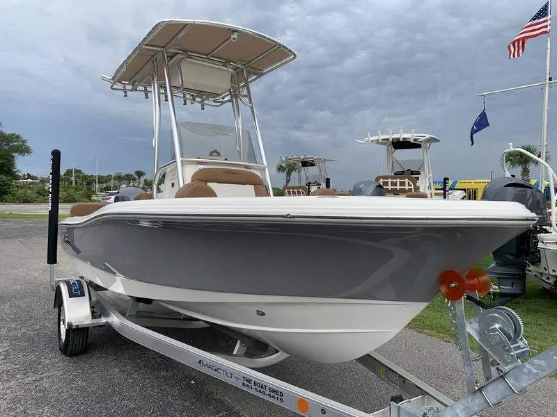 Slide: The Image of 2025 Pioneer Islander 180 boat on trailer, under cloudy sky, with flags in background. - 6