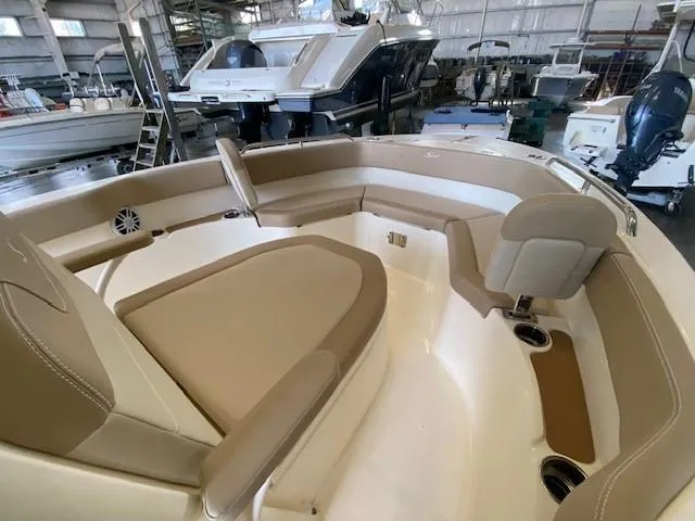 Slide: The Image of 2025 Scout 215 XSF boat interior with tan seating in a showroom. - 10