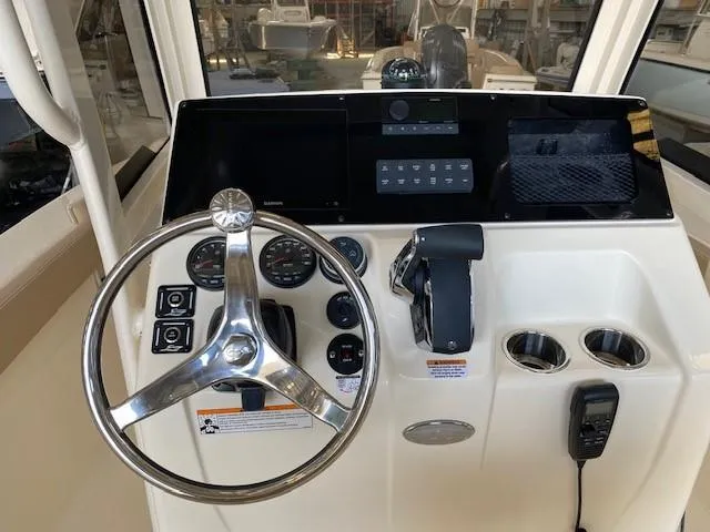 Slide: The Image of 2025 Scout 215 XSF boat dashboard with steering wheel, controls, and navigation system. - 7
