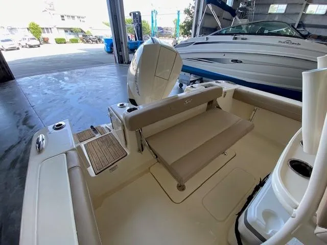 Slide: The Image of 2025 Scout 215 XSF boat interior with seating and outboard motor in a marina. - 8