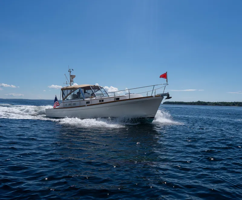 Slide: The Image of Grand Banks Eastbay 43 Ex 2000 cruising on open water under clear blue sky. - 16
