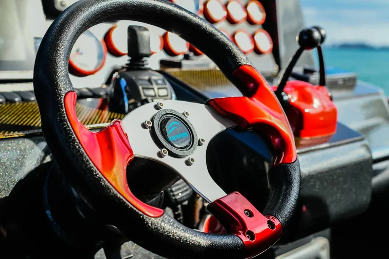 Slide: The Image of Steering wheel of a 2008 Fjord Express boat with red accents and control panel. - 22