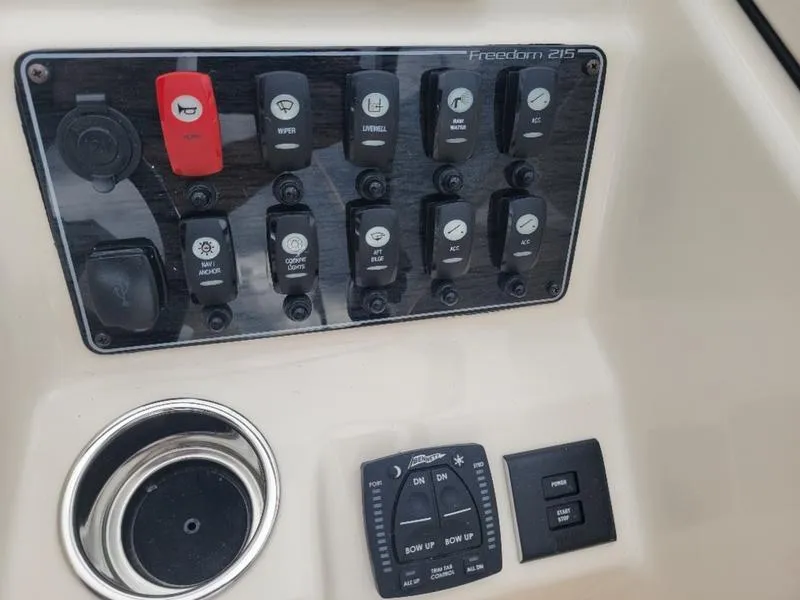 Slide: The Image of Control panel of 2025 Grady-White Freedom 215 boat with various switches and cup holder. - 16