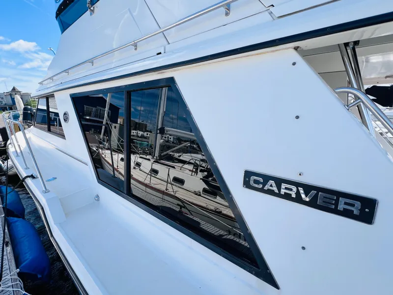 Slide: The Image of 1987 Carver 4227 Cockpit Motor Yacht docked, showcasing sleek design and reflective windows. - 10