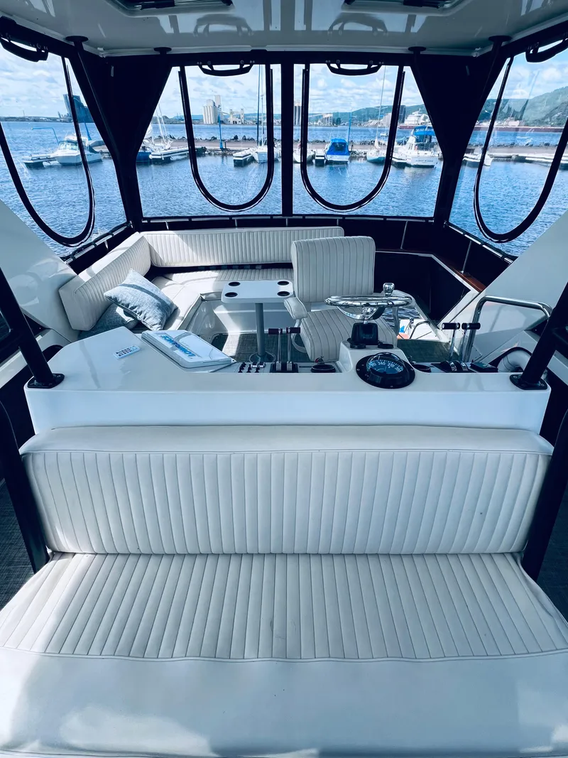 Slide: The Image of 1987 Carver 4227 Cockpit Motor Yacht interior with white seating, overlooking marina. - 12