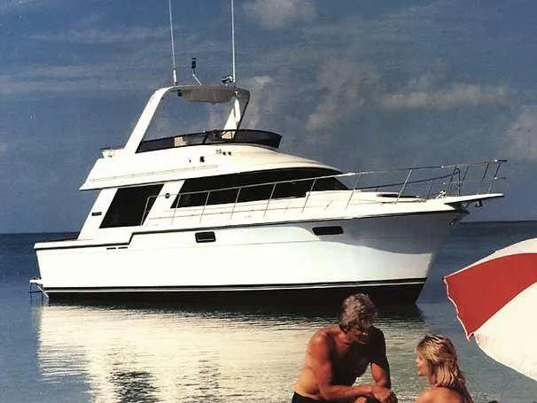 Slide: The Image of 1987 Carver 4227 Cockpit Motor Yacht anchored near beach with people relaxing. - 33