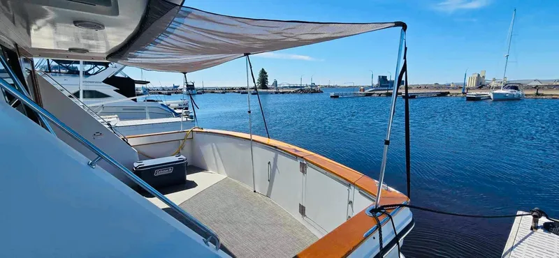 Slide: The Image of 1987 Carver 4227 Cockpit Motor Yacht docked, featuring spacious deck and canopy, overlooking marina. - 8