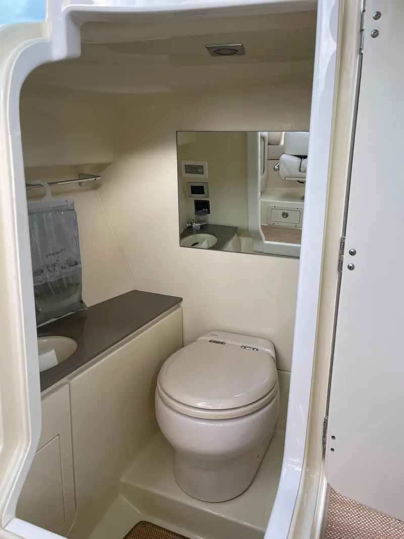 Slide: The Image of 2021 Chris-Craft 28 Launch GT boat bathroom with toilet, sink, and mirror. - 30