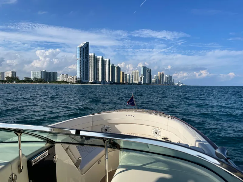 Slide: The Image of Chris-Craft 28 Launch GT 2021 boat cruising near a city skyline on a sunny day. - 5