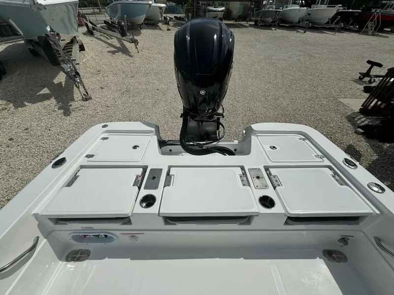 Slide: The Image of 2025 NauticStar 224 Bay boat with outboard motor in a gravel lot. - 14