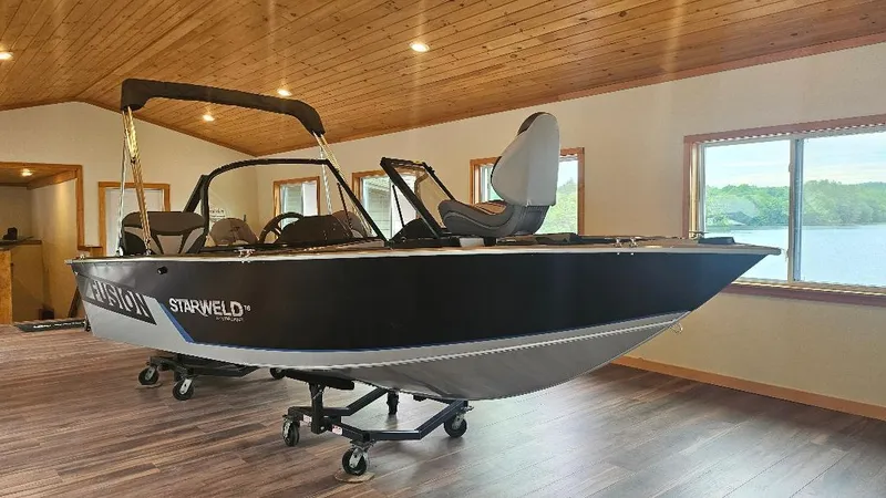Slide: The Image of 2025 Starcraft FUSION 16 DC boat displayed indoors on a trailer. - 0