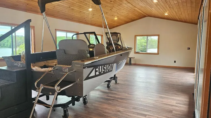 Slide: The Image of 2025 Starcraft FUSION 16 DC boat displayed indoors with wooden ceiling and large windows. - 2