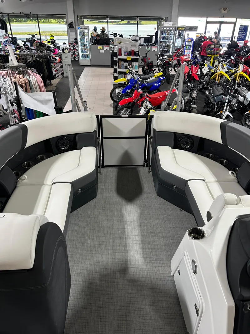 Slide: The Image of 2024 Trifecta 22RFCS boat interior with white seating, displayed in a showroom with motorcycles. - 4