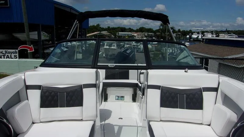 Slide: The Image of 2025 Monterey M 205 boat interior with white and black seating, docked under clear skies. - 4