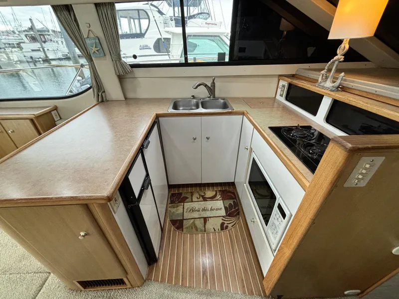 Slide: The Image of Compact kitchen area in a 2000 Bayliner 3788 Command Bridge Motoryacht with sink, stove, and microwave. - 17