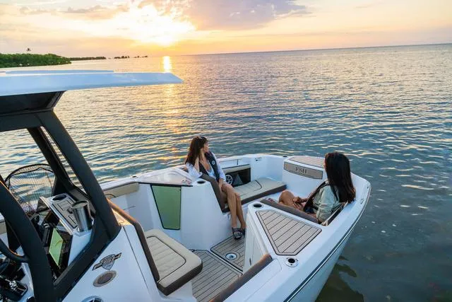 Slide: The Image of 2024 Yamaha Boats 255 FSH Sport H at sunset with two people relaxing on deck. - 16